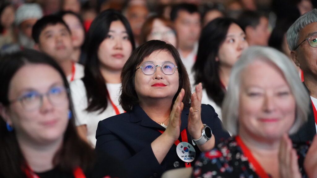 An image of a person sitting in the audience and clapping